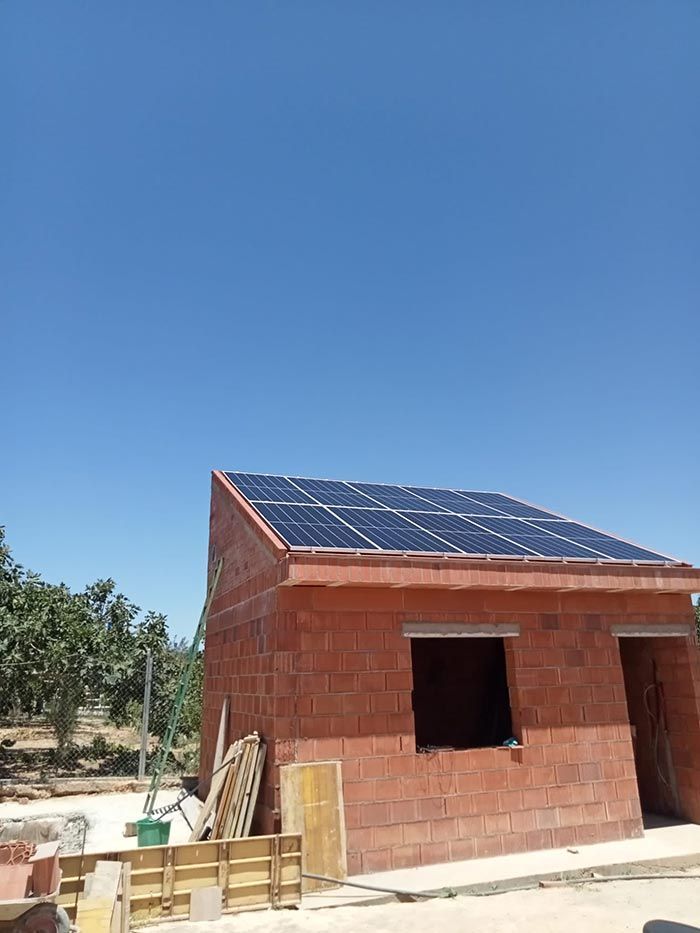 Paneles solares en el tejado de un edificio de ladrillo en construcción contra un cielo azul.