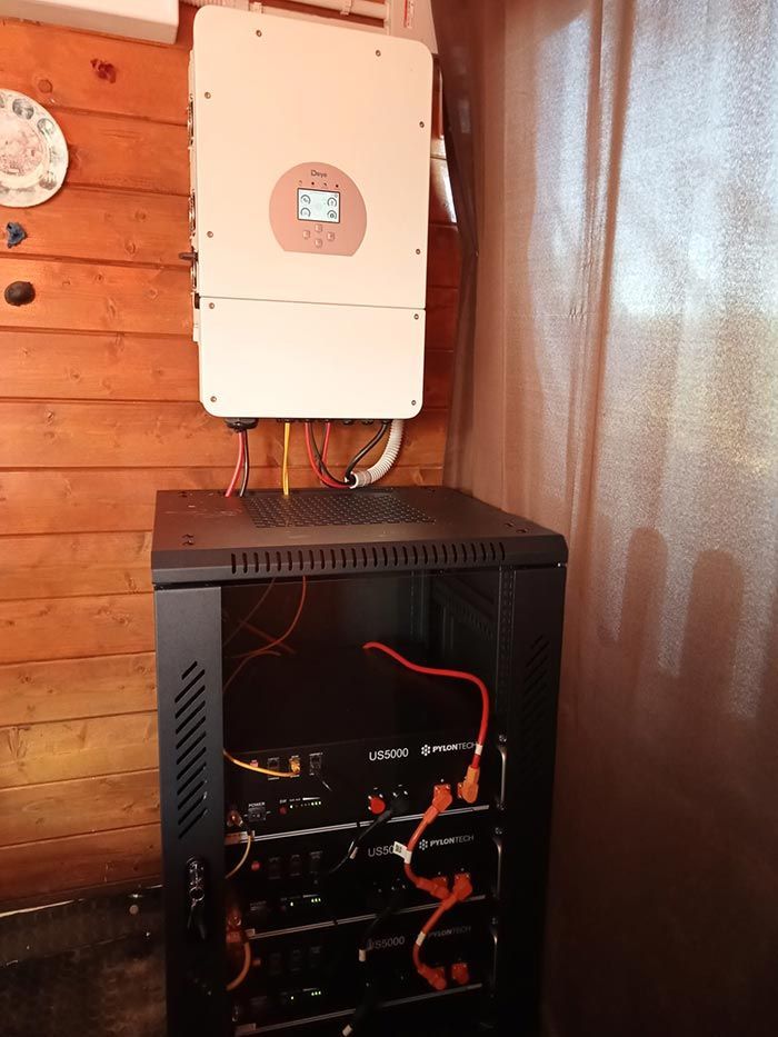 Inversor de energía solar montado sobre el soporte de la batería, conectado con cables, en el interior sobre una pared de madera.