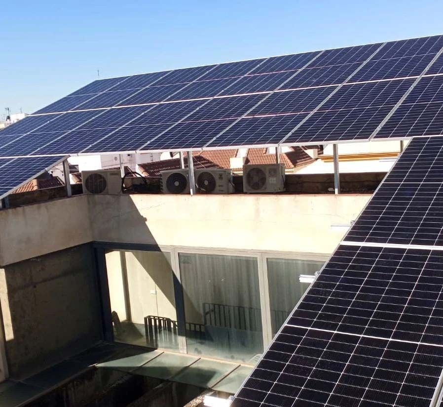 Paneles solares instalados en un tejado. Los equipos de aire acondicionado se ubican debajo de los paneles.
