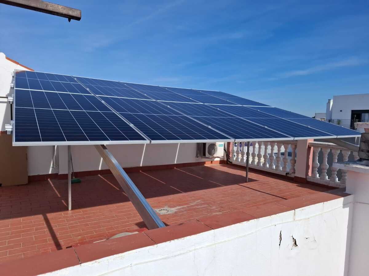 Paneles solares instalados en un tejado blanco bajo un cielo azul claro.