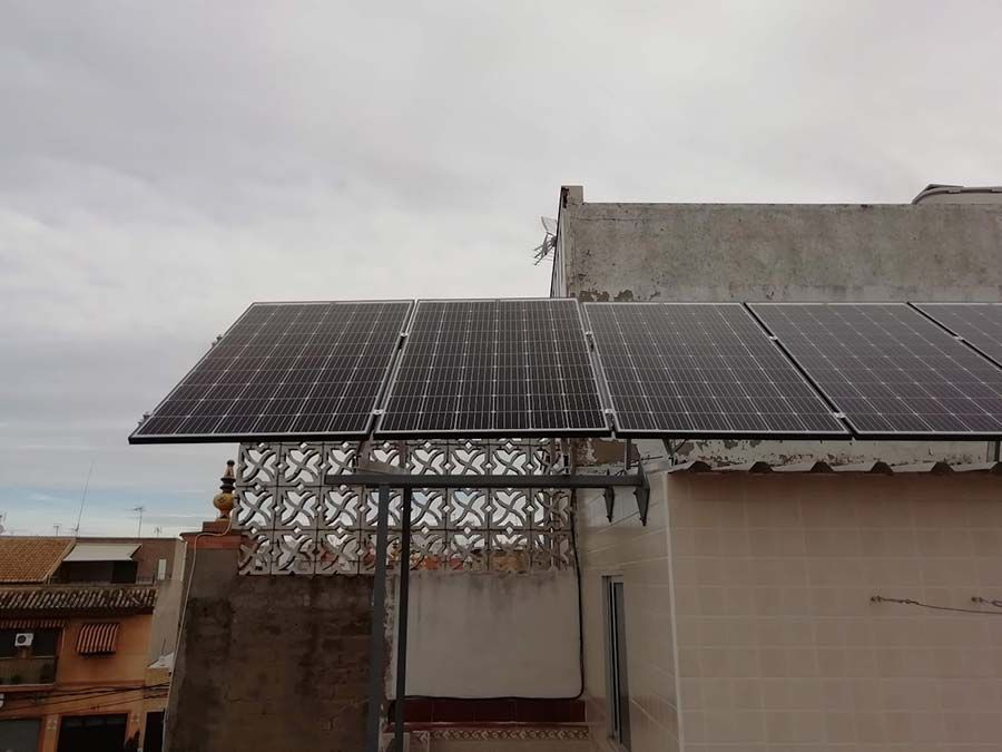 Paneles solares montados en el tejado de un edificio, captando la luz solar, con cielo nublado.