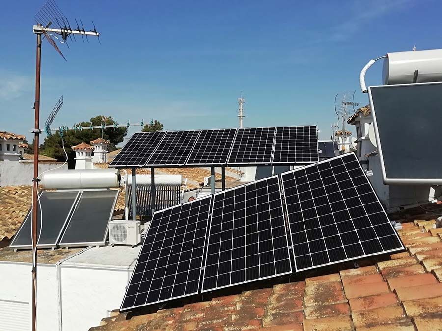 Paneles solares instalados en un tejado contra un cielo azul, incluidos calentadores de agua solares y una antena.