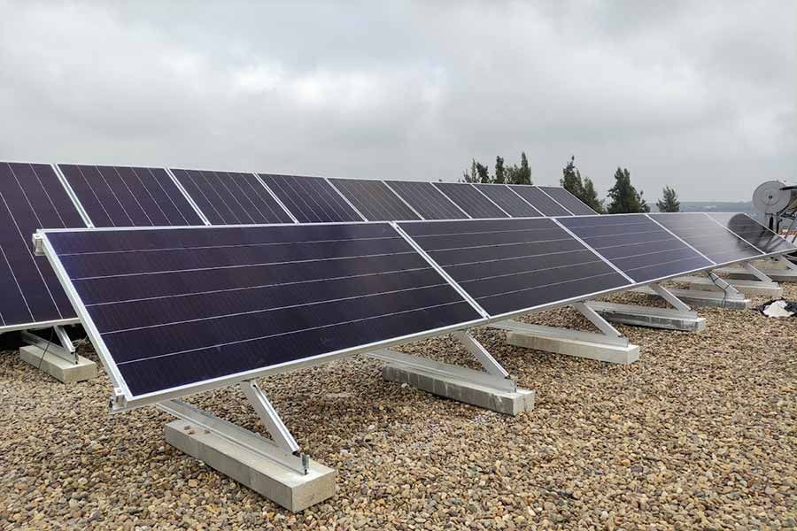Paneles solares sobre un tejado de grava, orientados hacia el cielo. Día gris y nublado.