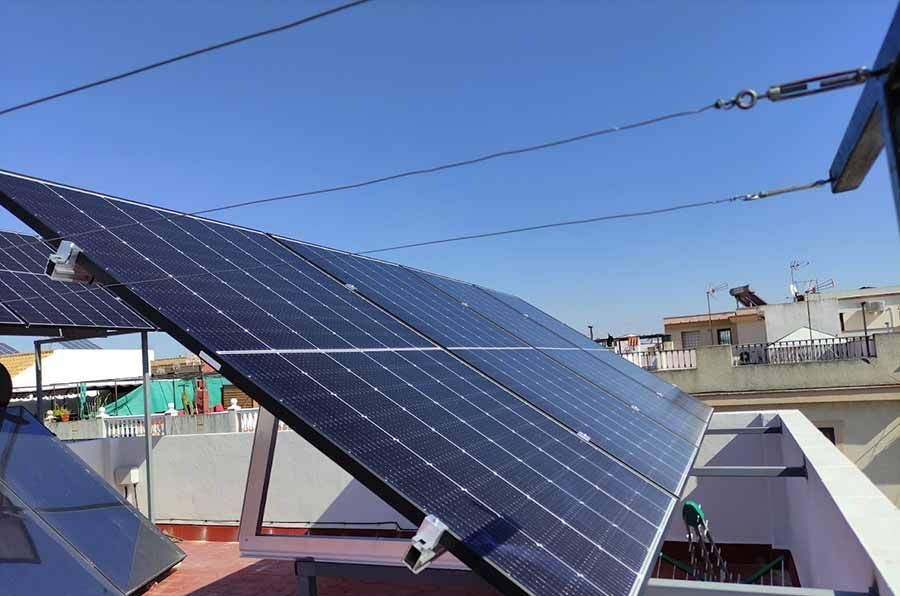 Paneles solares en un tejado, orientados hacia el sol, contra un cielo azul.