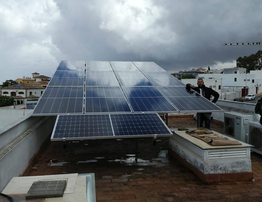 Paneles solares instalados en un tejado. Un hombre ajusta los paneles en un día nublado.