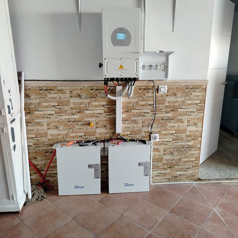 Sistema de energía solar instalado en una pared con baterías, inversor y componentes eléctricos.