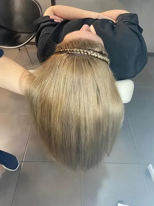 Una mujer está acostada boca arriba con la cabeza apoyada en una silla.