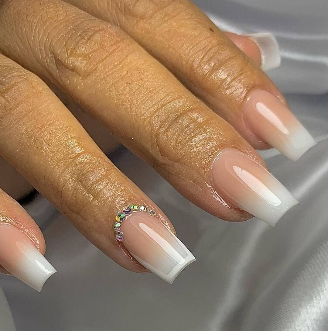 Un primer plano de las uñas de una mujer con diamantes de imitación.