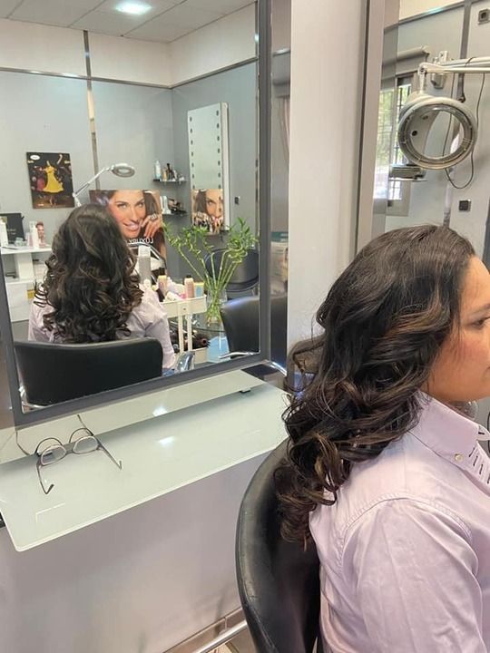 Una mujer está sentada en una silla frente a un espejo en una peluquería.