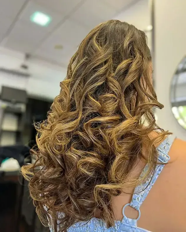 Una mujer con cabello largo y rizado se está peinando en un salón.