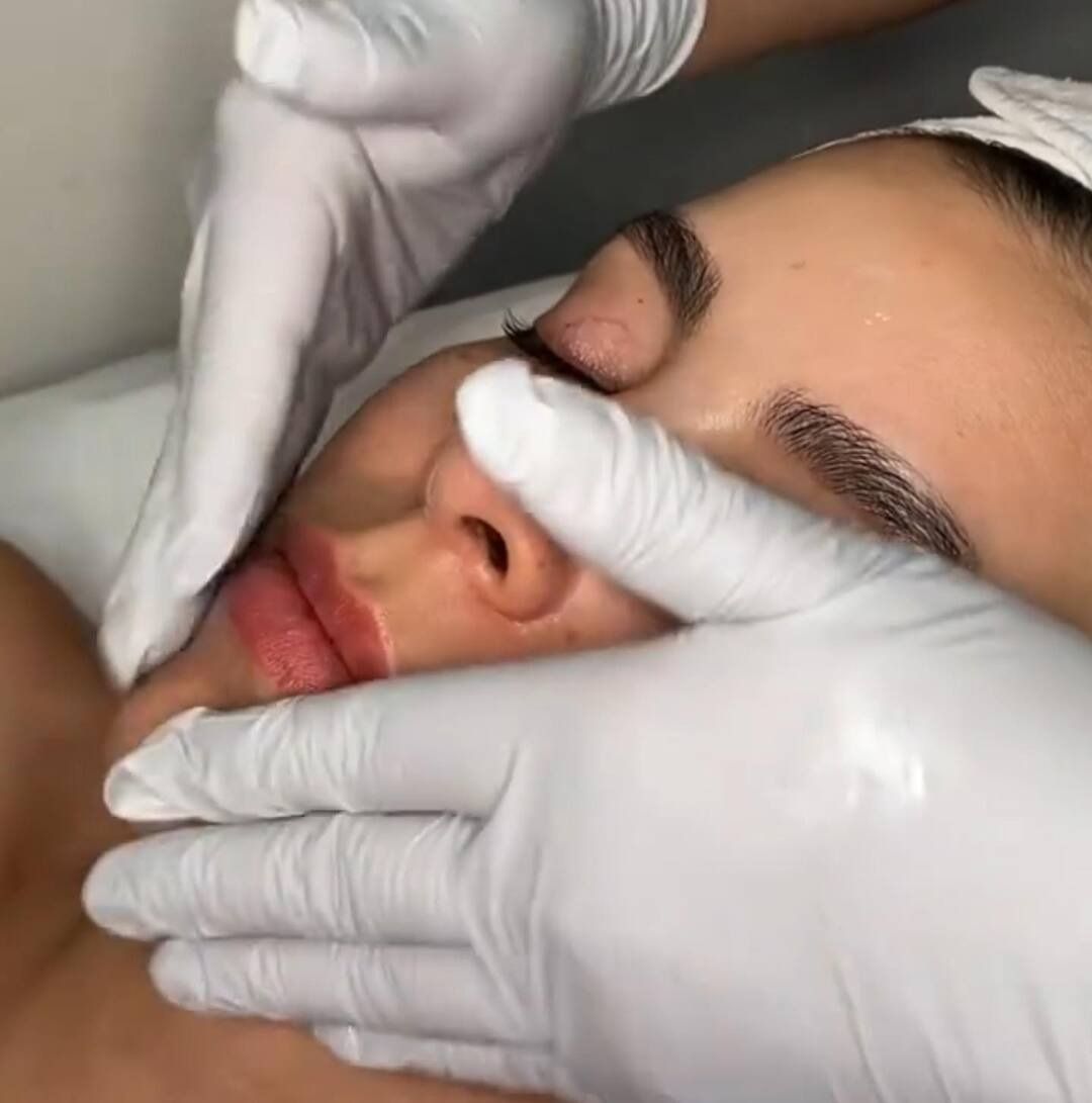 Una mujer está recibiendo un tratamiento facial con guantes blancos en la cara.