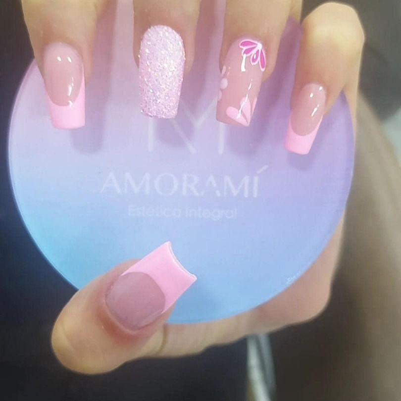 Las uñas de una mujer están pintadas de rosa y sostiene un objeto azul.