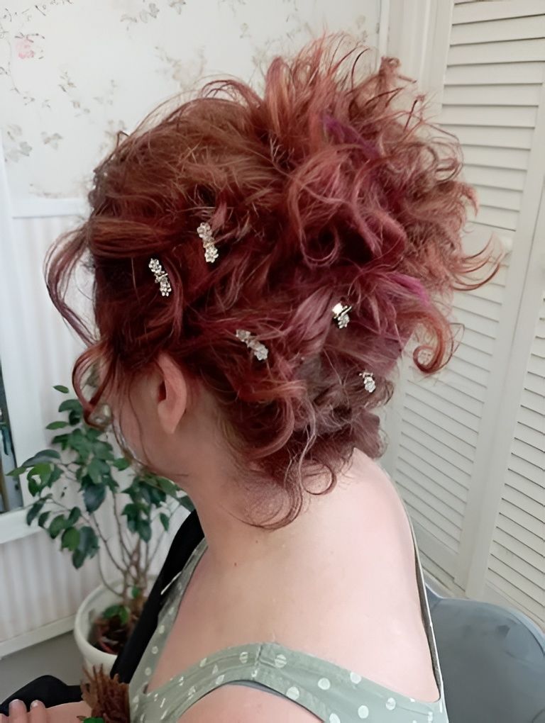 Recogido despeinado de pelo rojo rizado con horquillas plateadas, visto de perfil en una habitación con una planta y puertas de armario.