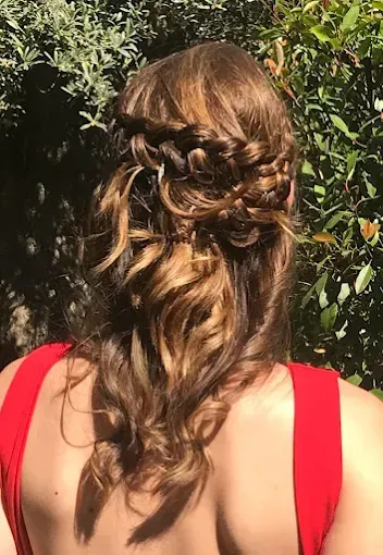 Mujer con un recogido trenzado castaño vista desde atrás, vestida con un vestido rojo al aire libre bajo la luz del sol.