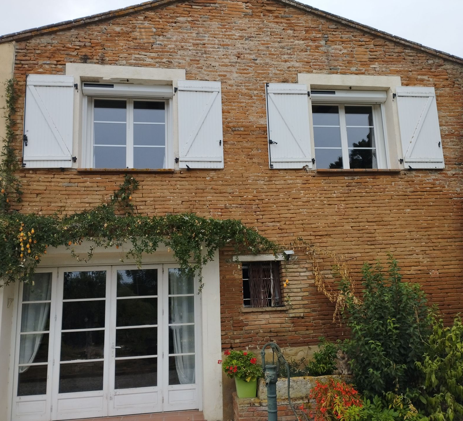 Maison en briques avec porte-fenêtre et 2 fenêtre avec volets roulants solaire