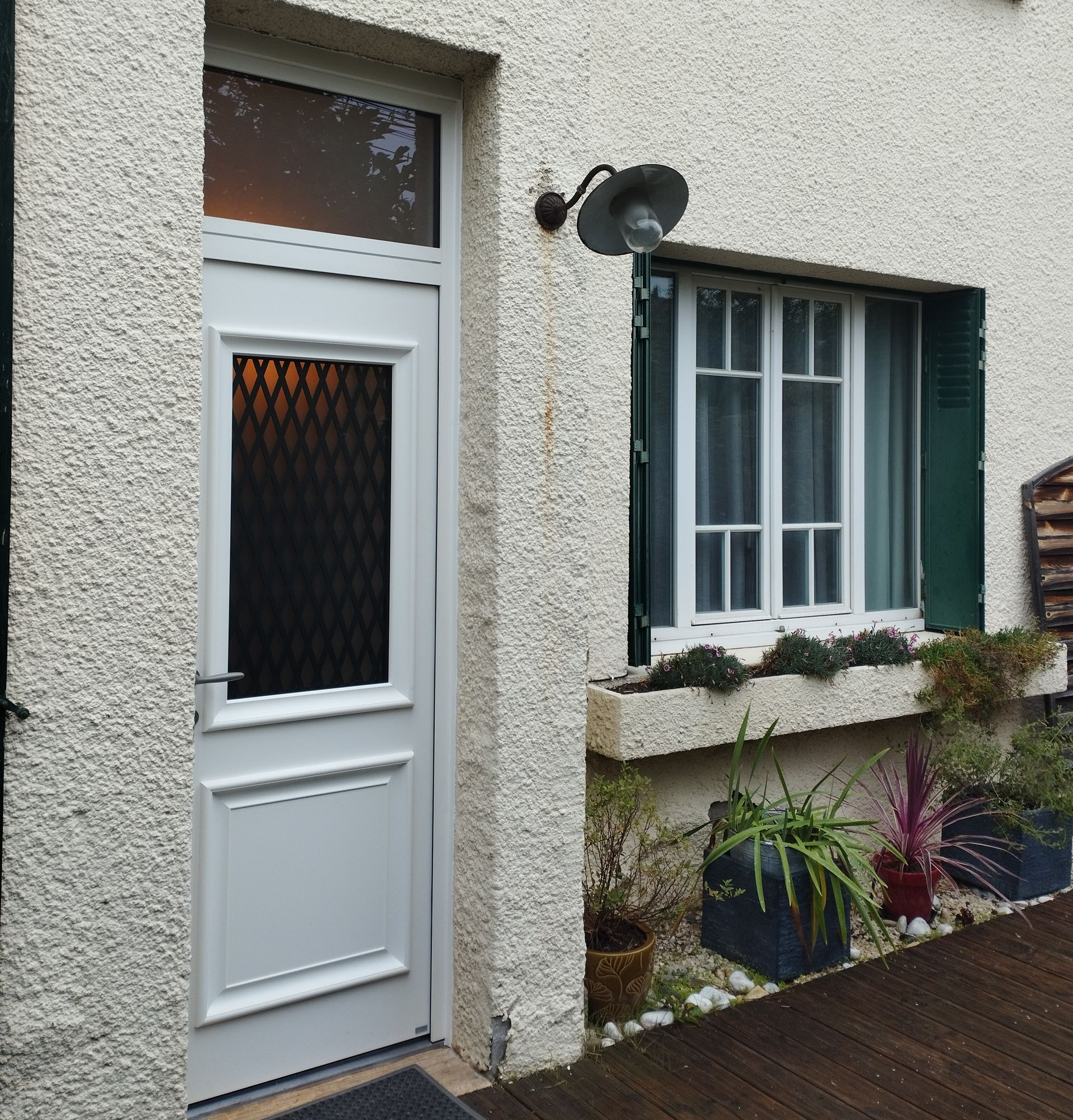 Entrée d'une maison avec porte blanche et fenêtre avec des petit bois.