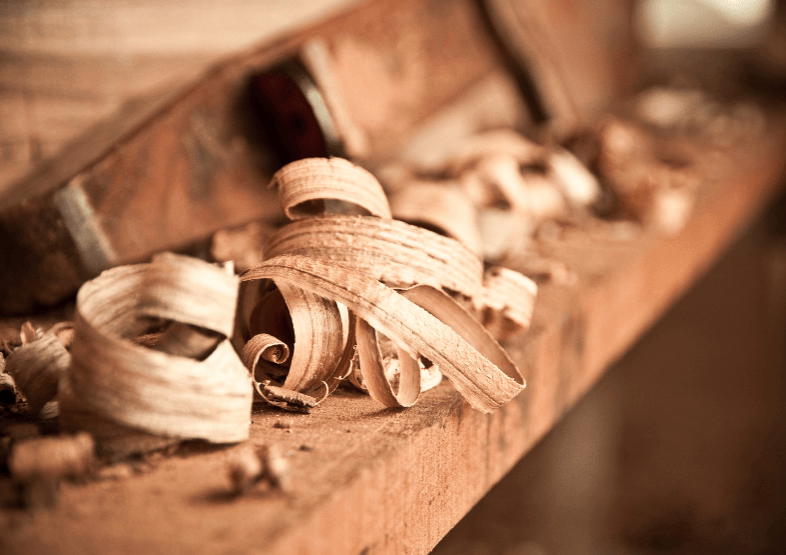 Copeaux de bois sur une surface en bois, avec un rabot flou en arrière-plan.