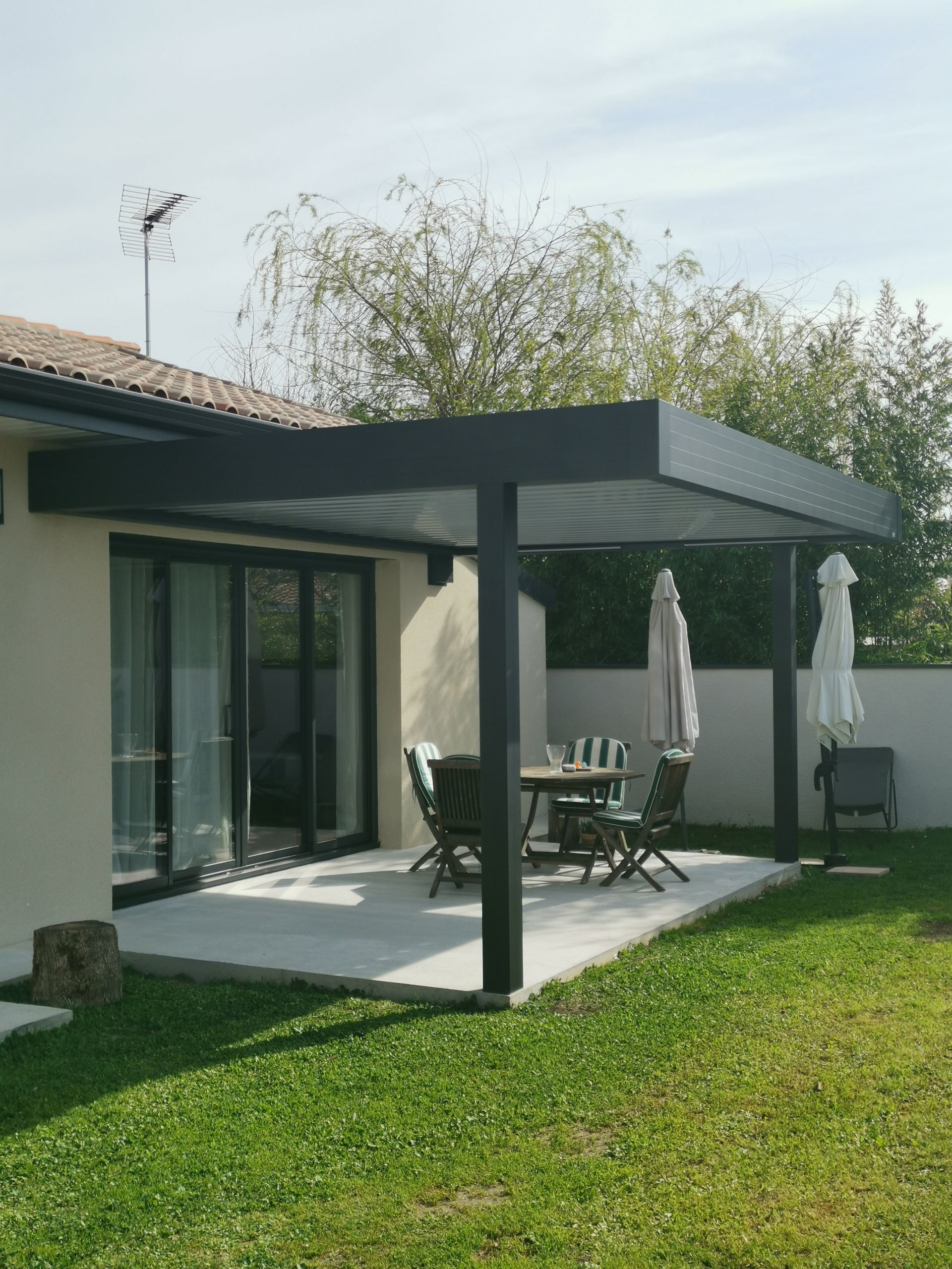 Abri voiture moderne attenant à une maison en briques, avec des accents de bois et de gris foncé.