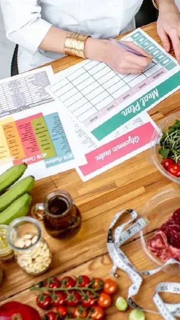 Una mujer está sentada en una mesa con verduras y una cinta métrica.