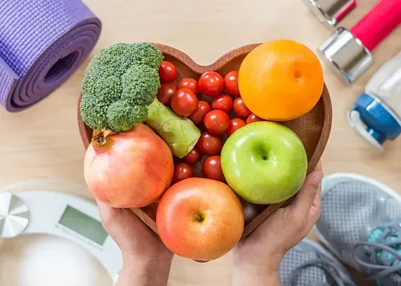 Una persona sostiene un recipiente con forma de corazón lleno de frutas y verduras.