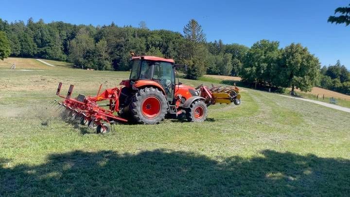 Ein roter Traktor fährt durch eine Wiese. Foto von Müller-Beef