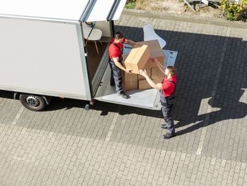 Dos hombres están cargando cajas en un camión de mudanzas.