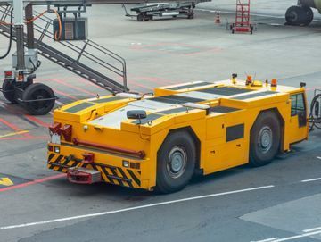Un camión amarillo está estacionado al costado de la carretera al lado de un avión.