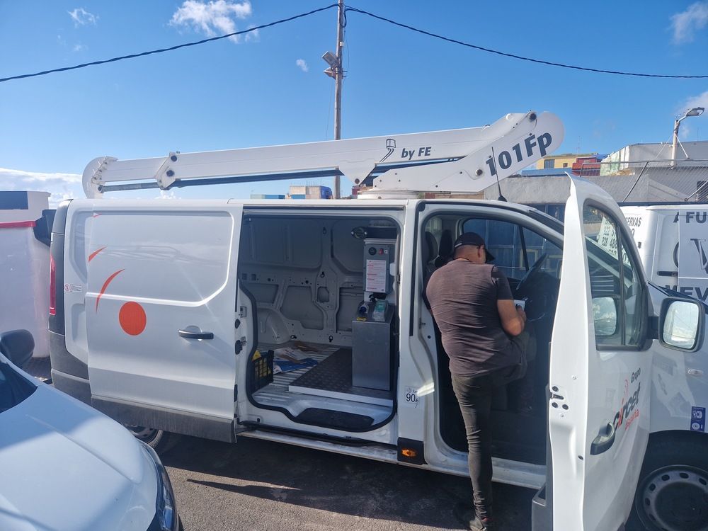 Un hombre sale de una camioneta blanca con una grúa encima.