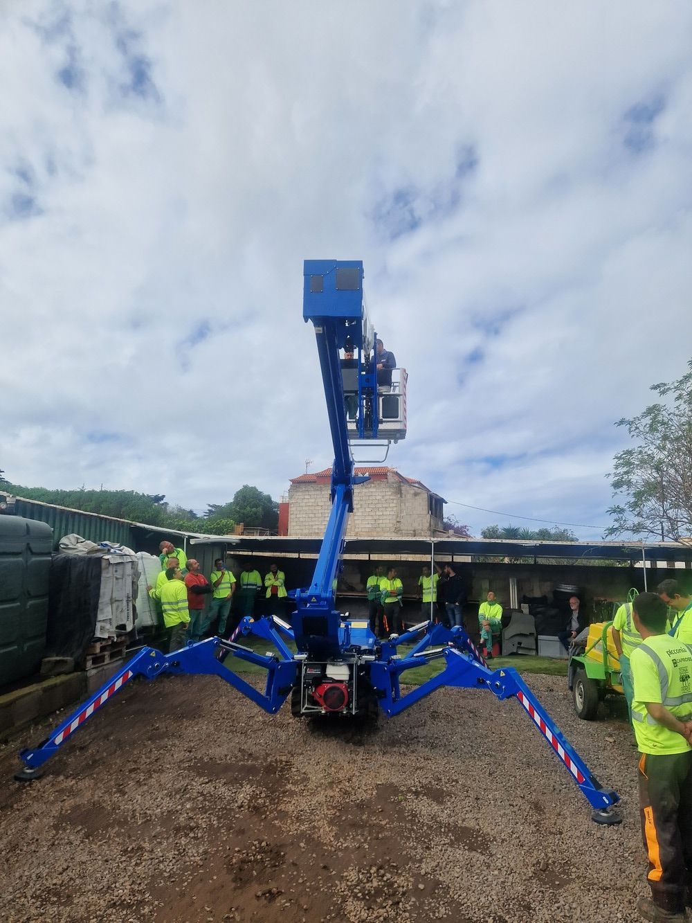 Un grupo de personas se encuentra de pie alrededor de un elevador araña azul.