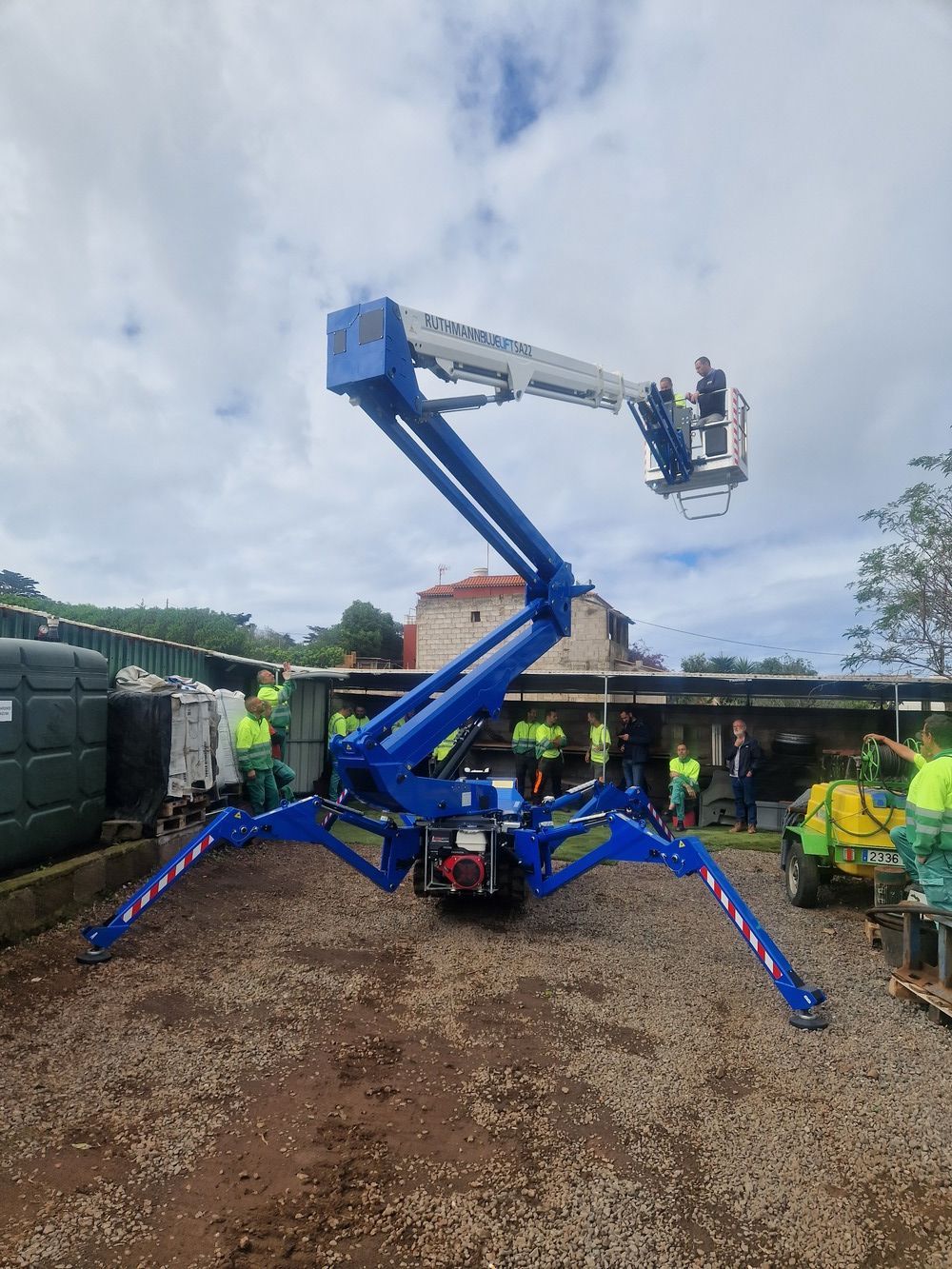 Un elevador de araña azul está estacionado en un lote de grava.