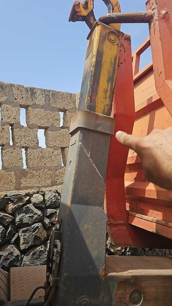 Una persona señala un trozo de metal delante de una pared de piedra.