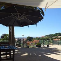 Comedor al aire libre con mesas, sombrillas y vista panorámica bajo un cielo azul brillante.