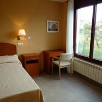 Dormitorio con cama, escritorio, silla, ventana con vista y mesa de noche.