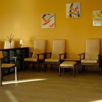 Sala de espera con sillas, arte de pared y una mesa pequeña.