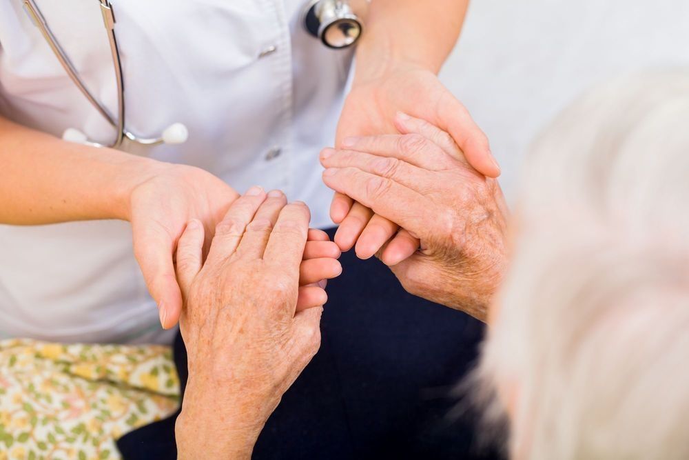 El proveedor de atención médica toma las manos de un paciente anciano, ofreciéndole apoyo y atención.