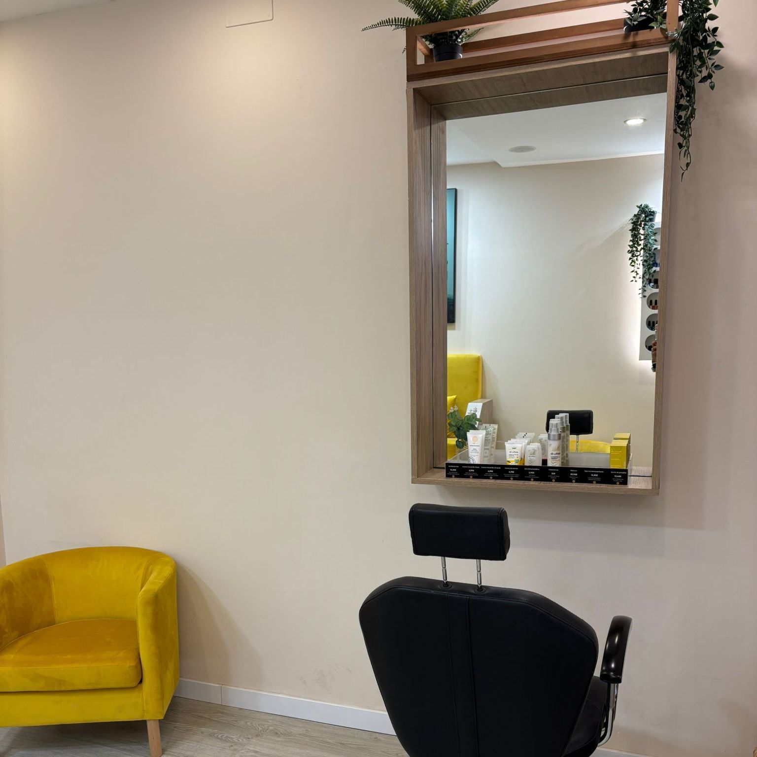 En una habitación luminosa, una silla de salón negra está frente a un gran espejo, con una silla decorativa amarilla