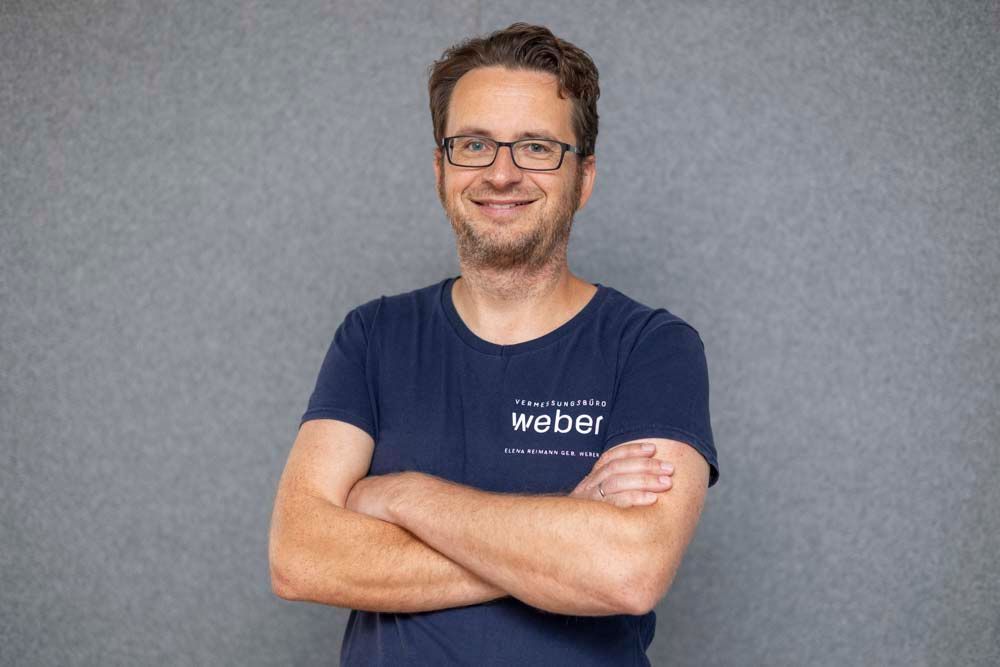 Ein Mann mit Brille und weißem Hemd lächelt in die Kamera.