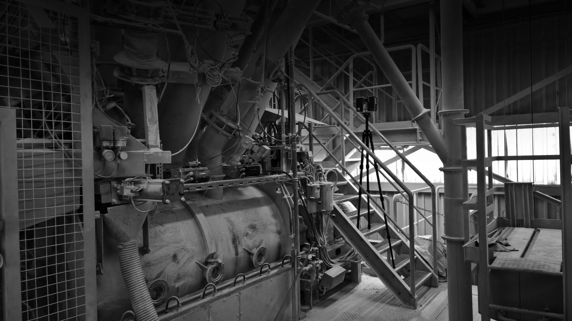 Industrielles Interieur, Maschinen mit Rohren und Treppen in einer Fabrikumgebung.