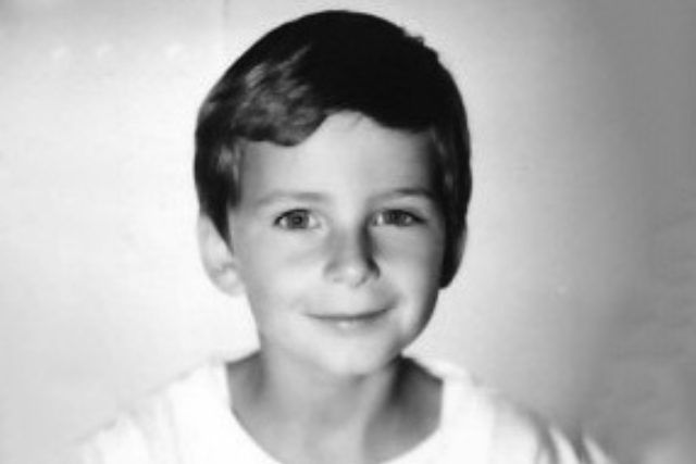 Auf einem Schwarzweißfoto lächelt ein kleiner Junge.