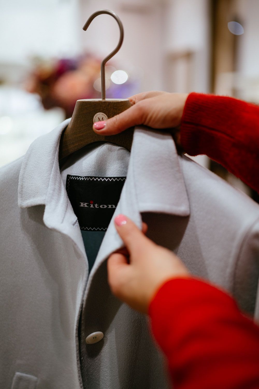 Eine Person hält in einem Geschäft einen Mantel auf einem Kleiderbügel.