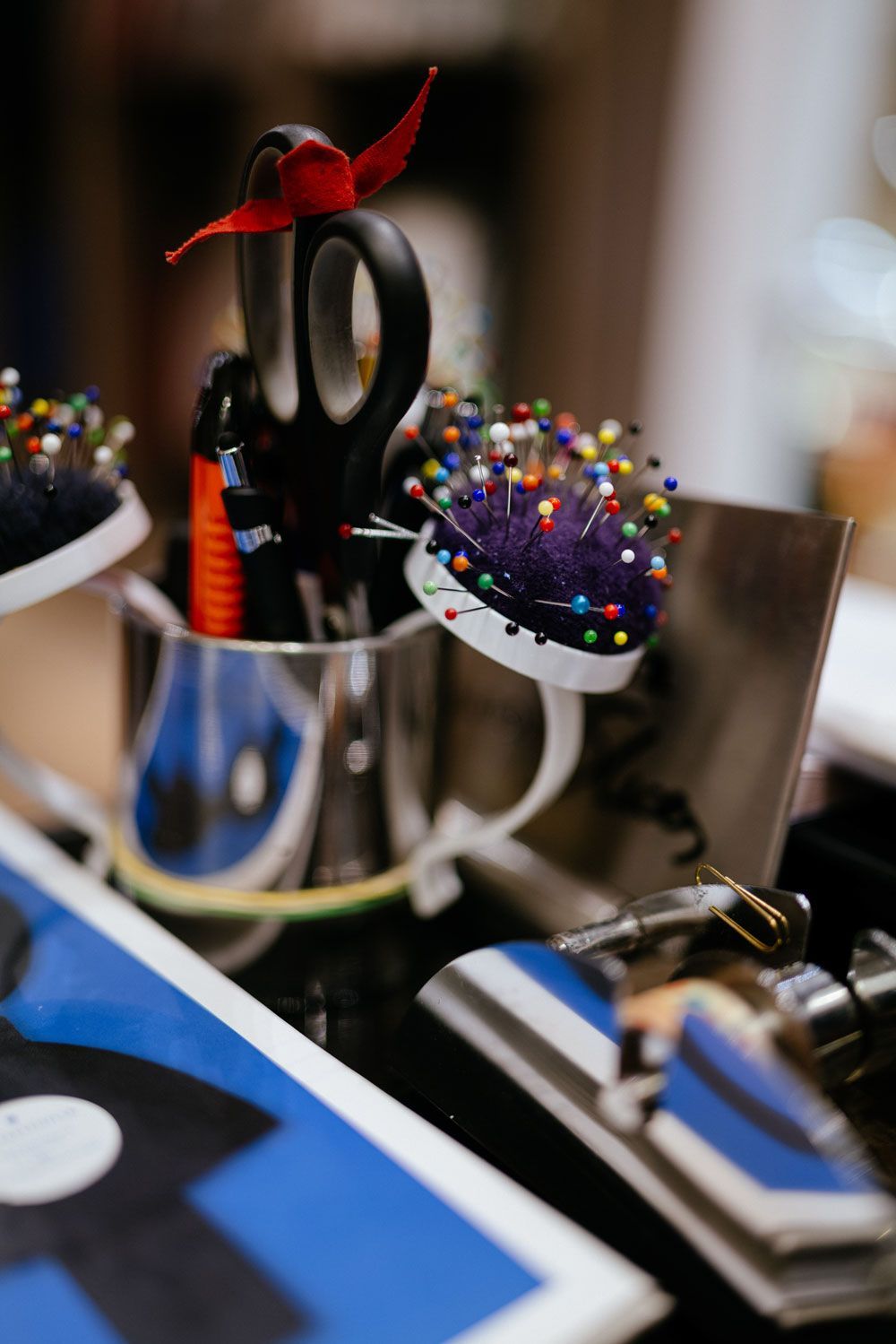 Eine Tasse gefüllt mit Scheren, Nadeln und Bürsten auf einem Tisch.