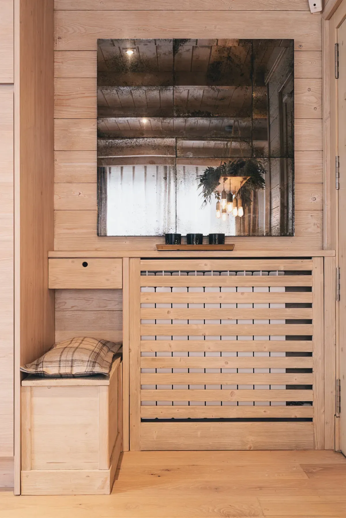 Banco de sauna con paneles de madera y cubierta de rejilla para el calentador con una toalla a la izquierda.