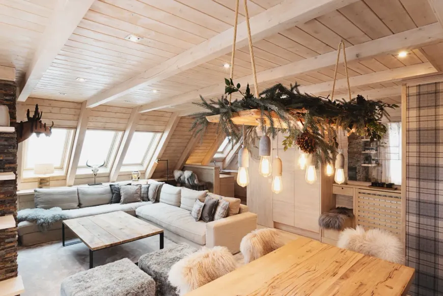 Acogedora sala de estar rústica con sofá modular gris, mesas de madera y lámparas colgantes con motivos vegetales.