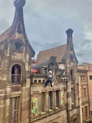 Una persona se encuentra suspendida de un cable en el exterior de un edificio peculiar con aspecto de castillo