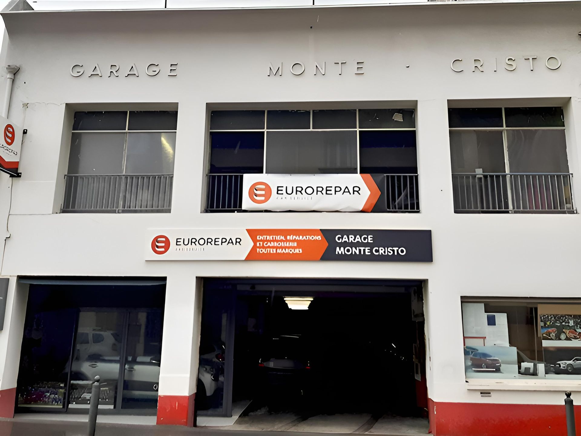 Garage Monte-Cristo : bâtiment blanc, panneau orange Eurorepar, porte de garage ouverte, panneau noir avec détails orange et blancs.