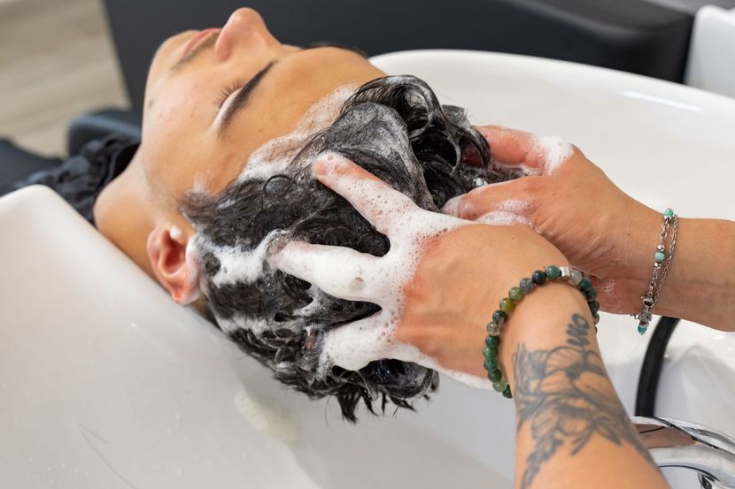 Une personne effectuant un shampoing sur un homme.