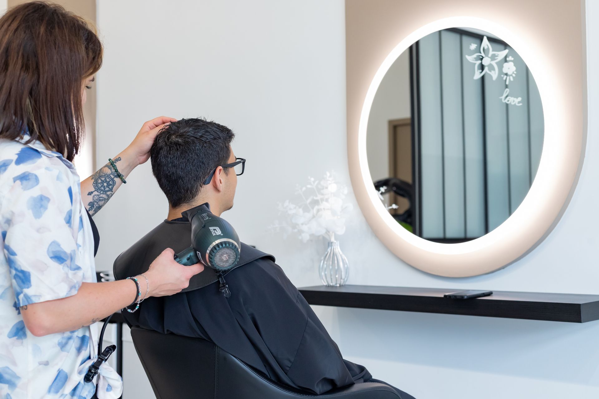 Une femme coiffant un homme.