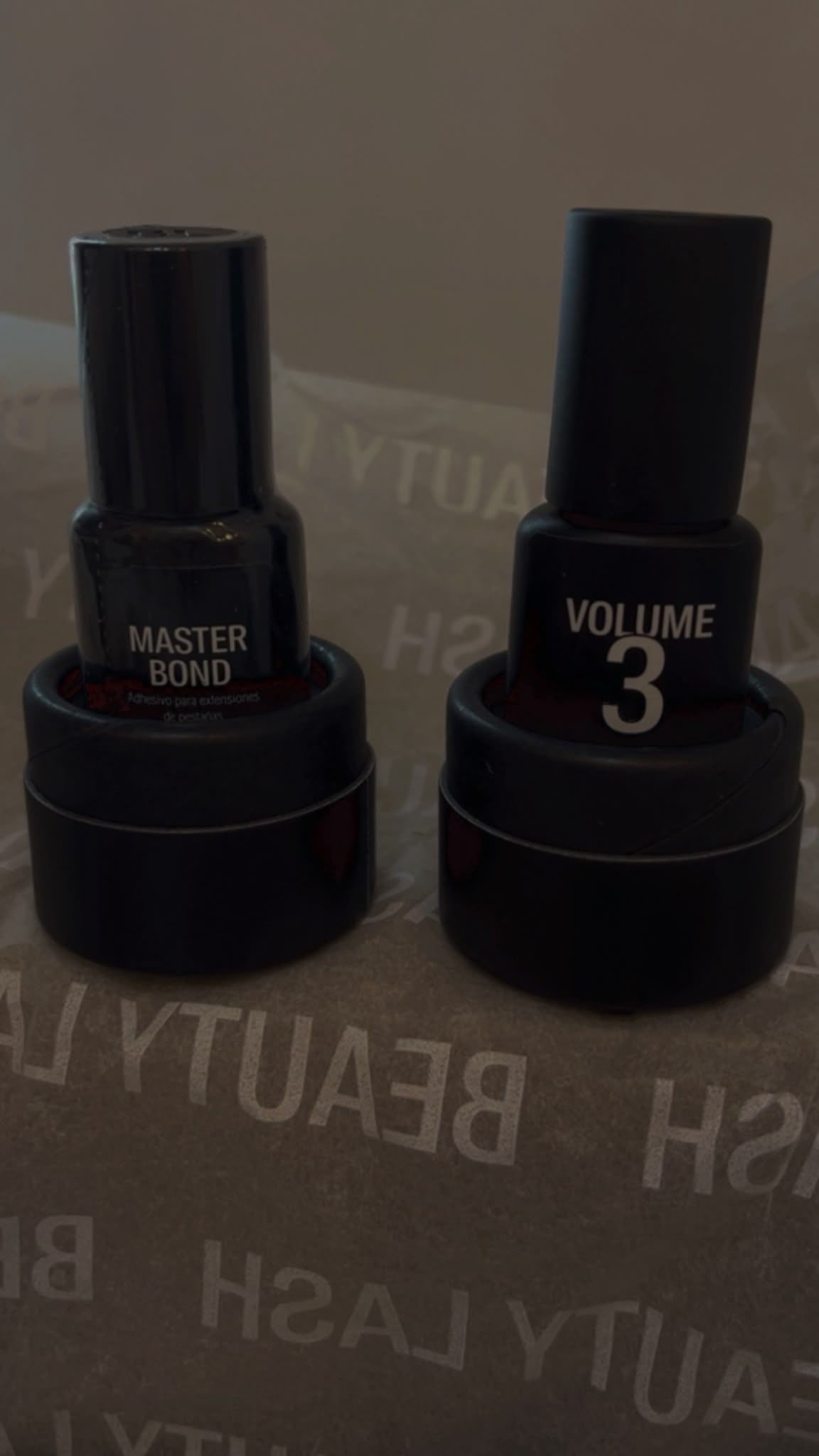 Dos frascos de esmalte de uñas negro con sus tapas puestas, etiquetados como “Master Rose” y “Volume 3”