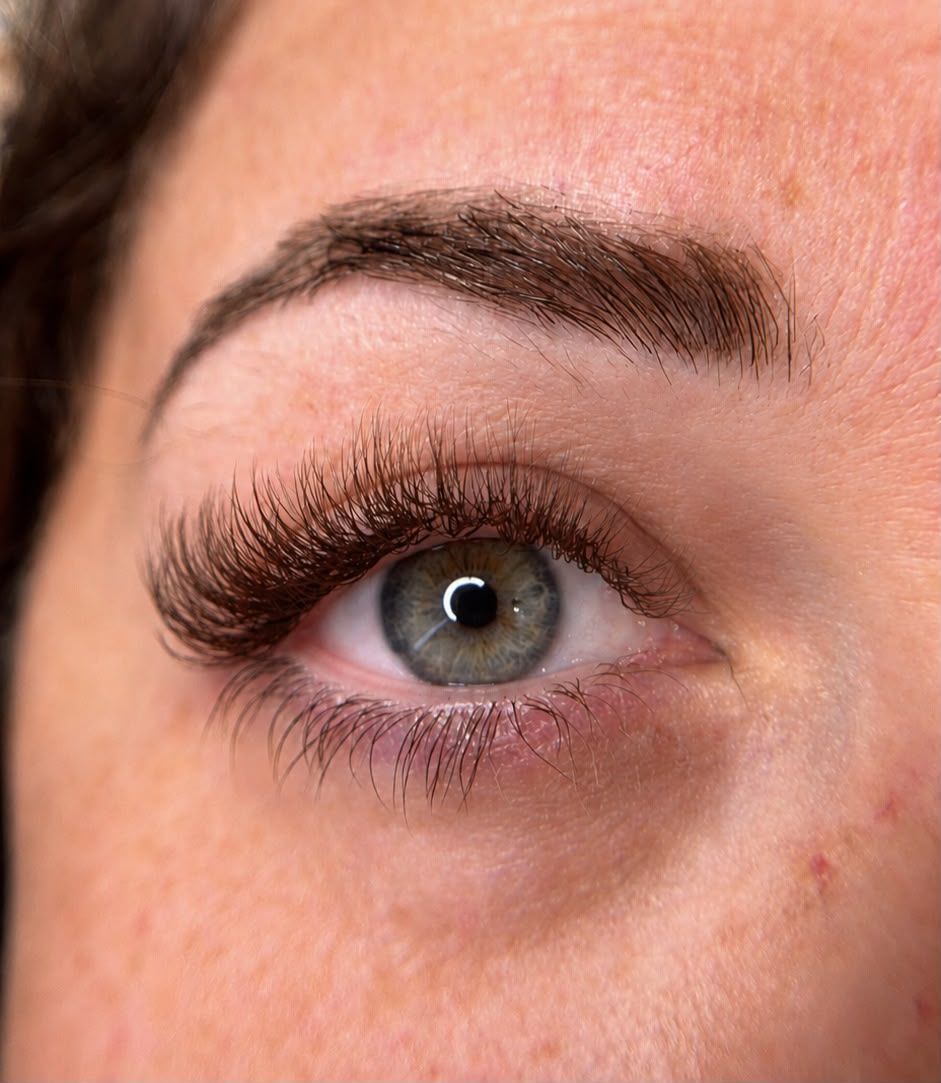 Primer plano de un ojo humano con pestañas largas y una ceja oscura.
