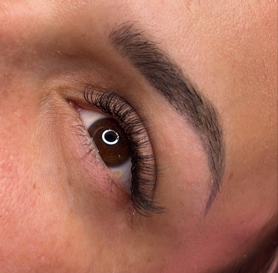 Primer plano de un ojo marrón con pestañas largas y una ceja bien definida.